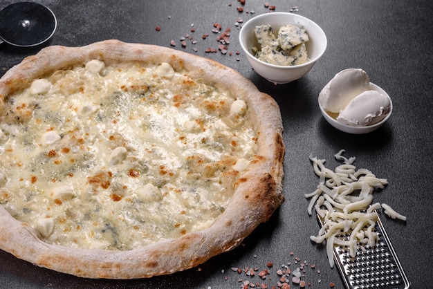 Foto pizza italiana deliziosa fresca con quattro tipi di formaggio su uno sfondo di cemento scuro. cucina italiana