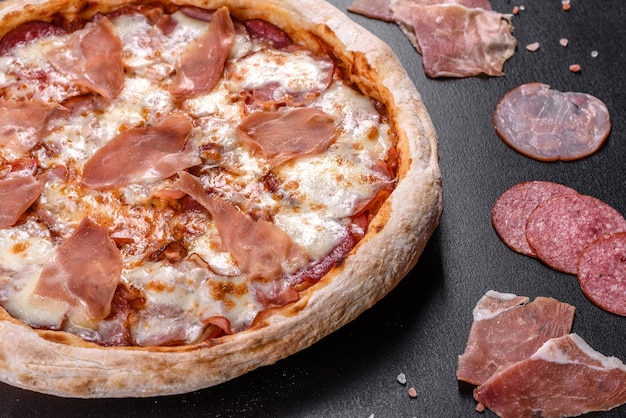 Fresh delicious Italian pizza with a prosciutto on a dark concrete background. Italian cuisine