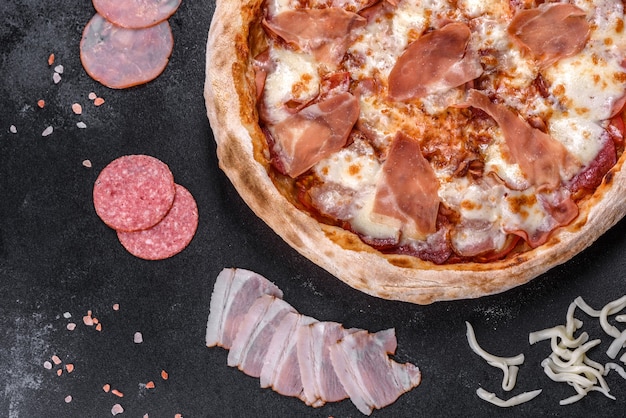 Fresh delicious Italian pizza with a prosciutto on a dark concrete background. Italian cuisine