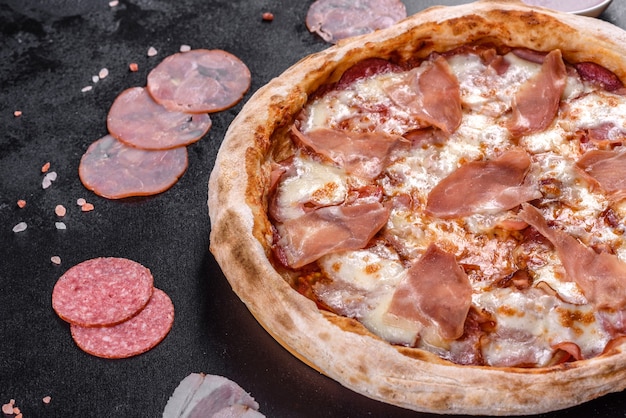 어두운 콘크리트 배경에 프로슈토를 곁들인 신선한 맛있는 이탈리아 피자. 이탈리아 요리