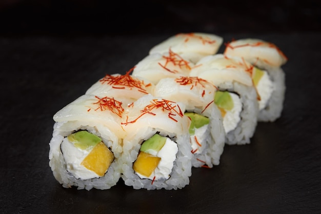 Fresh delicious Japanese sushi with avocado cucumber and caviar on dark background