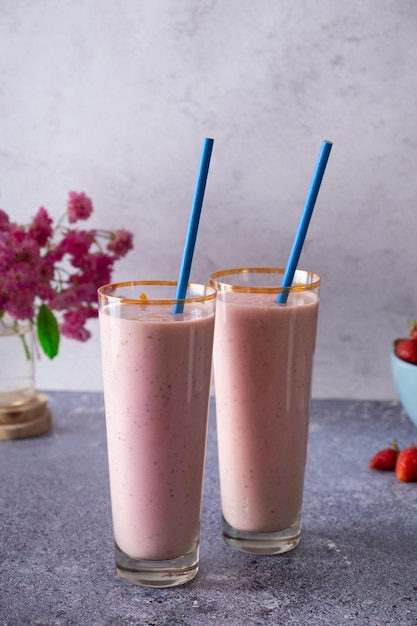 Fresh delicious milk strawberry smoothies in glass glasses and flowers on the table Summer drink concept