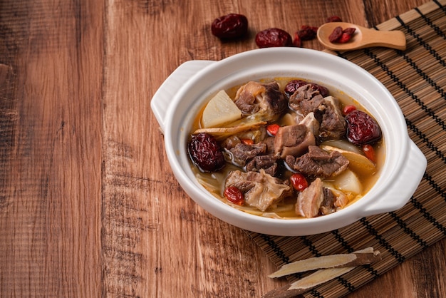 Foto piatto caldo di montone fresco e delizioso con verdure e erbe medicinali cinesi come bacche di goji e angelica cinese dong quai.