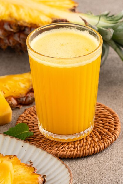 Foto fresco delizioso frullato di succo di ananas bevanda fredda in tazza di vetro su sfondo grigio tavolo