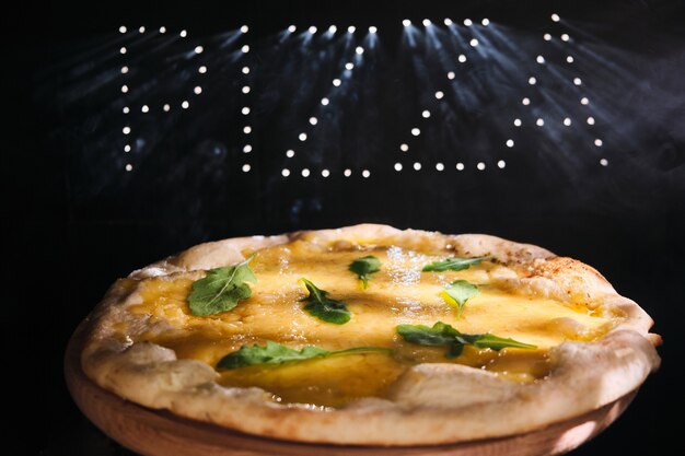 Fresh delicious pizza four cheeses with arugula Pizza with a spectacular light effect and smoke