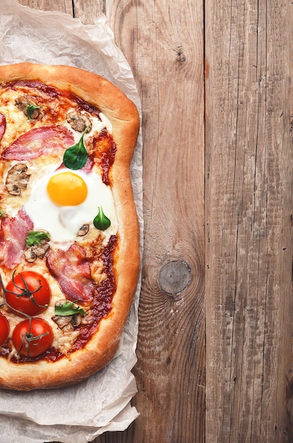 Fresh delicious pizza from the oven with egg, prosciutto and tomato