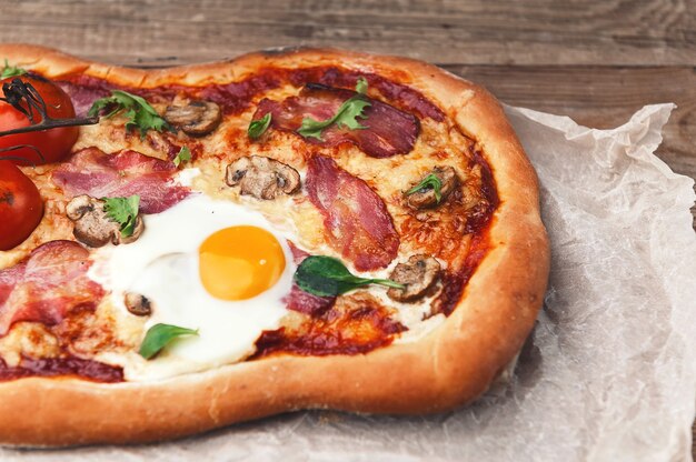 Fresh delicious pizza from the oven with egg, prosciutto and tomato