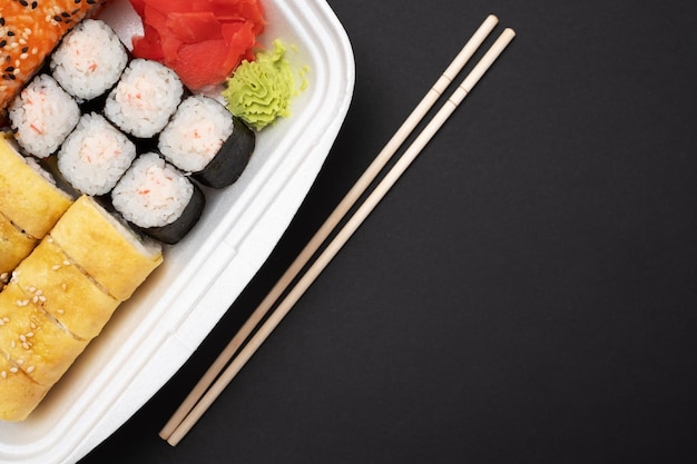 Fresh delicious sushi rolls on a black wall with copyspace