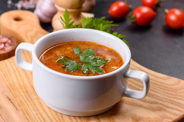 Zuppa di pomodoro deliziosa fresca con spezie e prezzemolo in una ciotola bianca su una tavola di legno