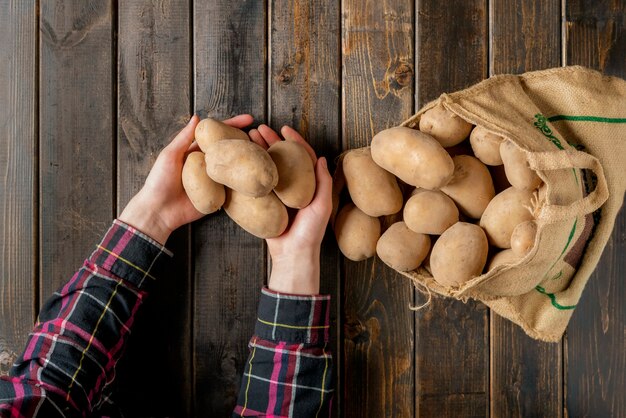 Fresh dirty potatoes in the cloth bag isolated on wooden surface b