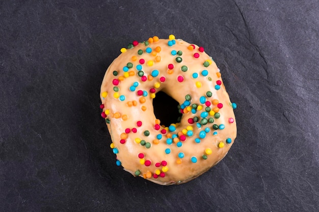 Fresh donut with toppings on a dark background.