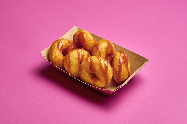 Fresh donuts with drizzled caramel on a pink background.