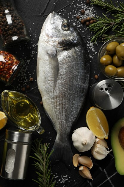 Fresh Dorado fish and cooking ingredients on black background, top view