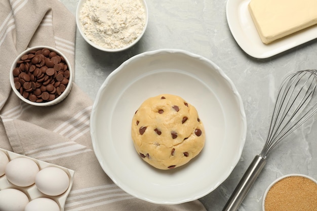 fresh dough and different ingredients for cooking chocolate chip cookies on light grey marble table flat lay