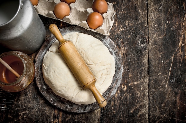 Fresh dough with ingredients on a wooden background