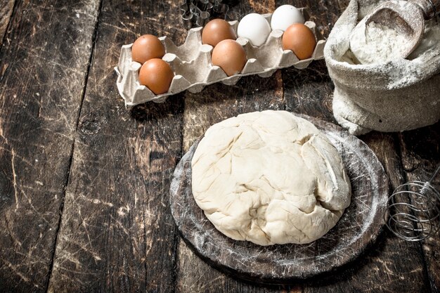 Fresh dough with ingredients. On a wooden background.