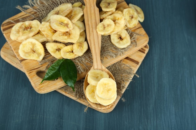 Fresh and dried banana slices on cutting board on wooden background