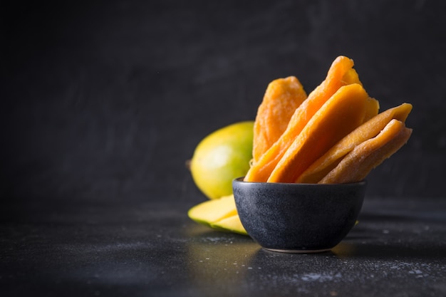 Fresh and dried mango chips on black