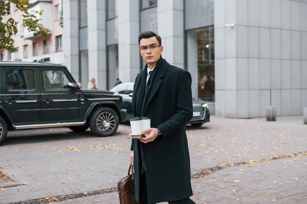 Fresh drink Businessman in black suit and tie is outdoors in the city