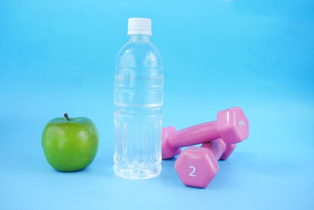 Fresh drinking water apple and a pink color dumbbell on table