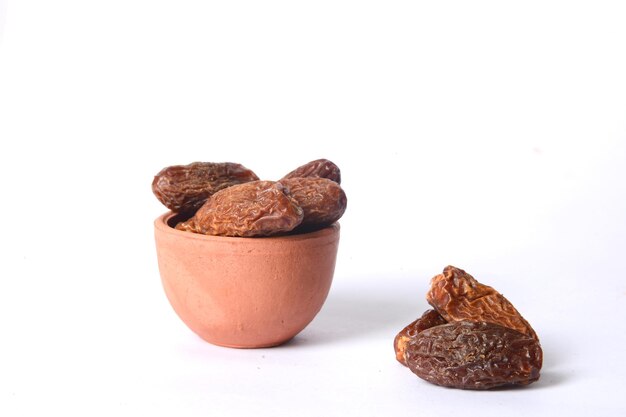 Photo fresh dry dates in the wooden bowl, organic, border white background, wooden background.