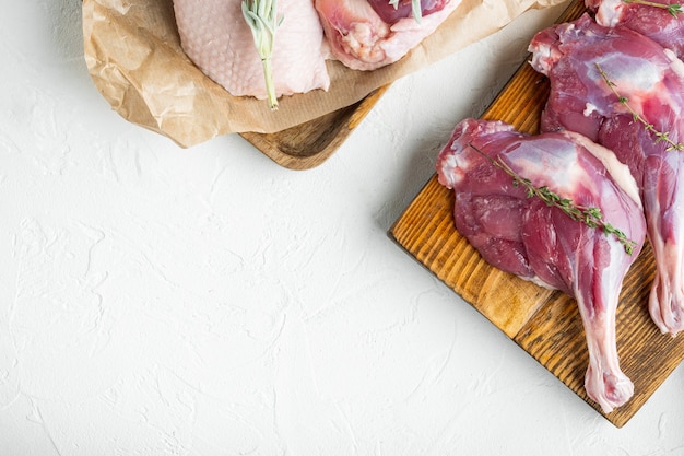 Fresh duck leg and breast meat set, on wooden cutting board, on white stone