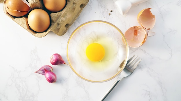 Photo fresh egg yoke in glass bowl with cooking ingredients on top view