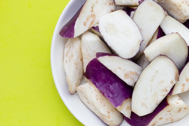 Fresh eggplant in white bowl on green background copy space