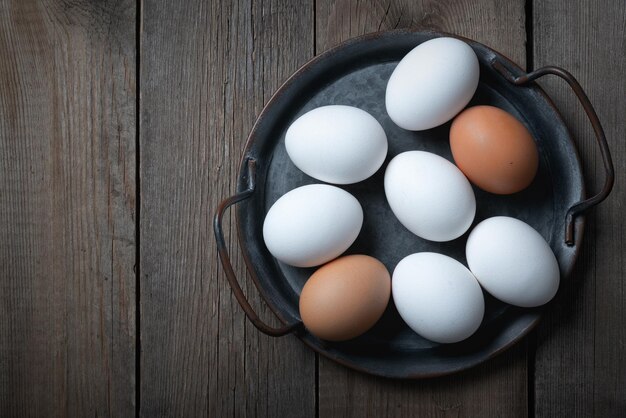 Fresh eggs in a metal tray on an old wooden table