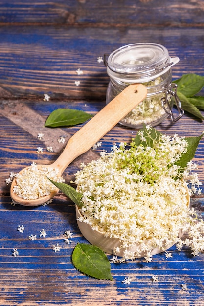 Foto fiori di sambuco freschi. ingrediente per il concetto di cibo sano. luce dura moderna, ombra scura. sfondo di tavole vintage blu, spazio di copia