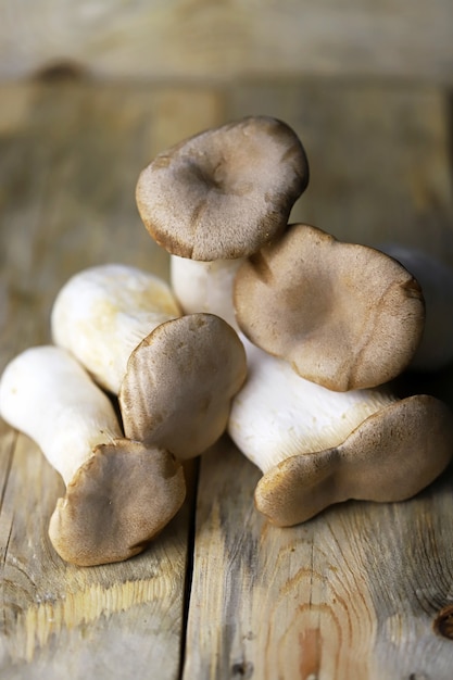 Fresh eringi mushrooms on a wooden surface.