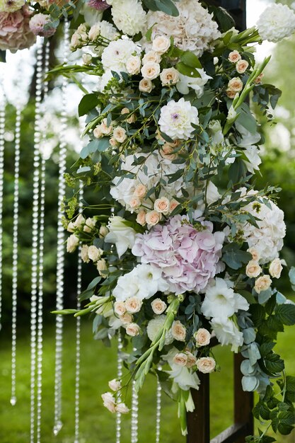 Fresh exotic flowers on the wooden wedding arch outdoors