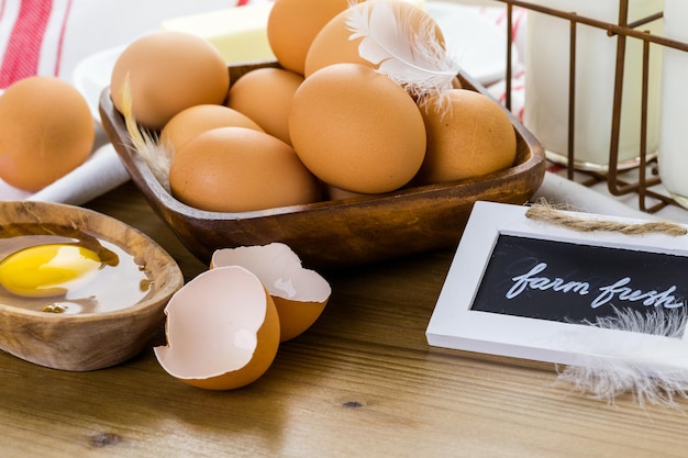 Fresh farm eggs, milk and butter on wood table.