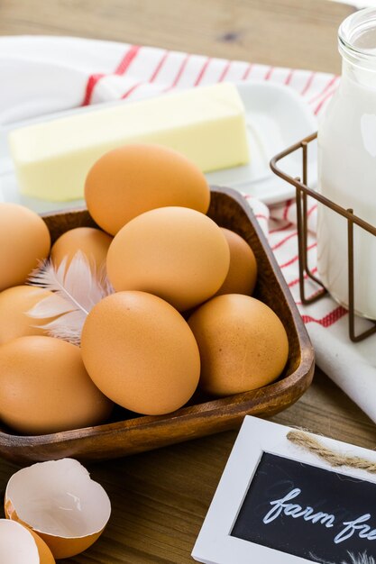 Fresh farm eggs, milk and butter on wood table.