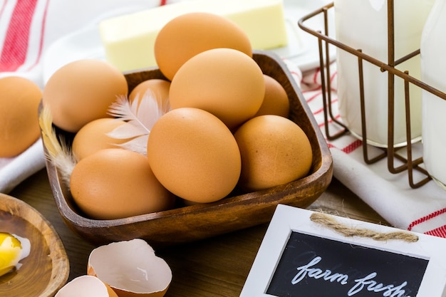 Fresh farm eggs, milk and butter on wood table.
