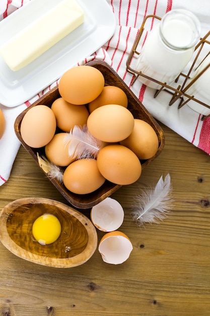 Fresh farm eggs, milk and butter on wood table.