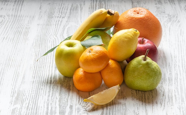 Fresh farm fruits Apples pears oranges bananas and tangerines on a dark wooden background The concept of healthy vegetarian food from the market