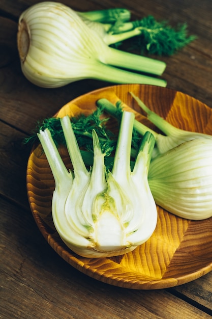 Fresh fennel bulbs in plate on wooden.