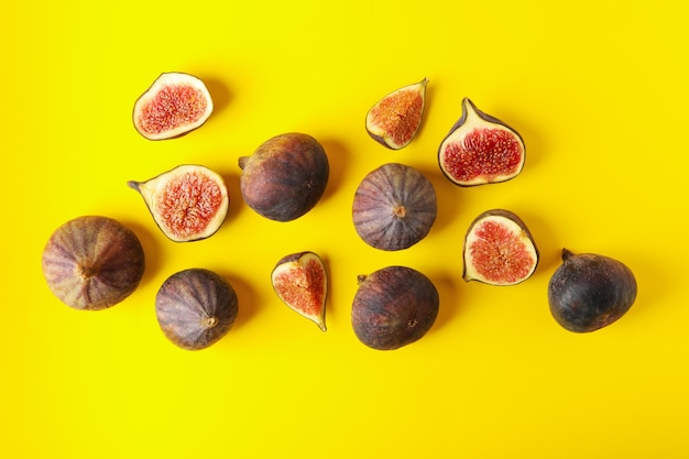 Fresh fig fruits and slices on yellow, top view