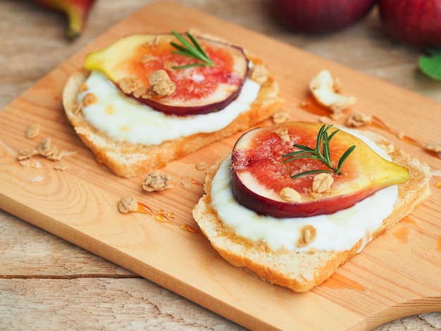 Fresh fig sliced on yogurt and bread topping with granola and honey for breakfast