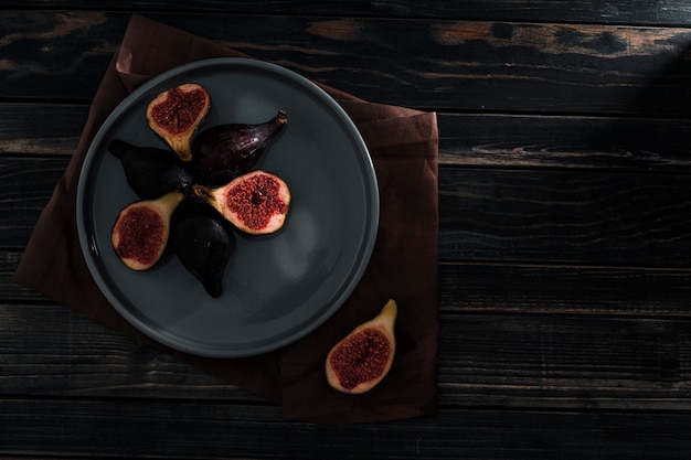 Fresh figs are whole and cut into slices on plate in a low key