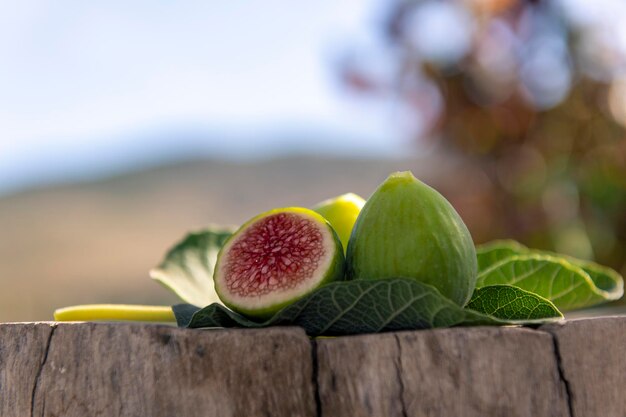 Fresh figs on fig tree leaf on wooden base blurred background