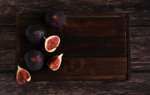 Photo fresh figs whole and in section on a wooden background closeup