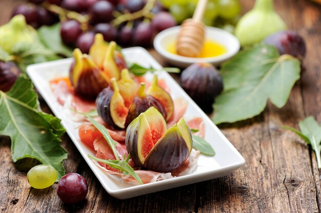 Fresh figs with ham on a white plate