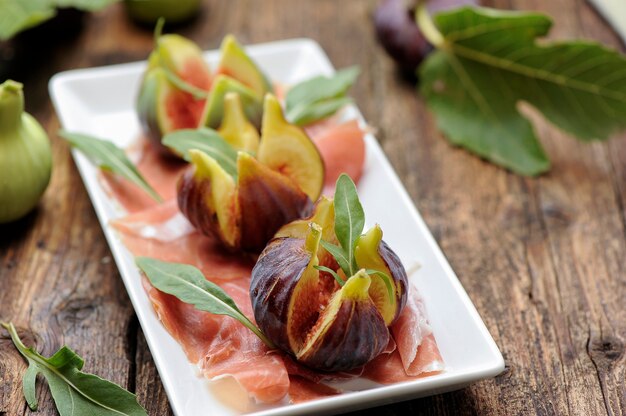 Fresh figs with ham on a white plate