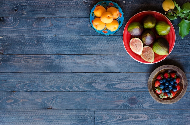 Fresh figs with peaches apricots blueberries strawberries on a wooden  background.