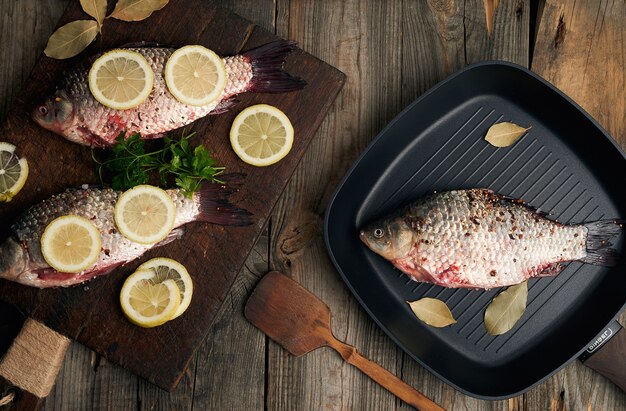 Fresh fish in crucian scales on a brown old wooden cutting board, food seasoned with spices