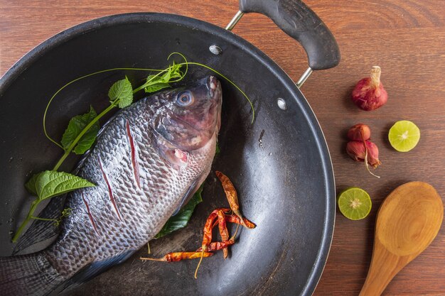 Свежая рыба на сковороде и специи для приготовления