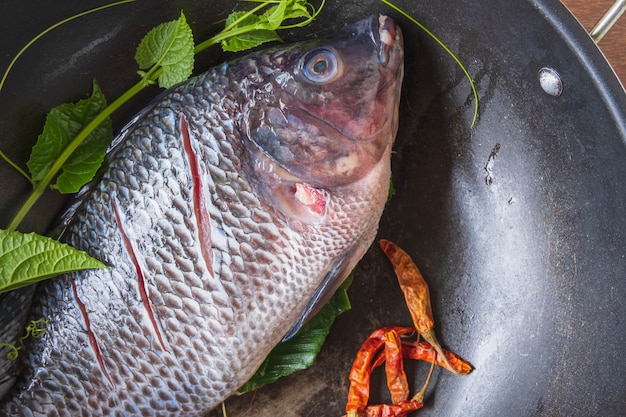 Pesce fresco in padella e spezie per cucinare