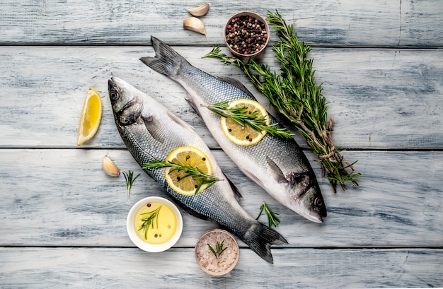 Branzino di pesce fresco. pesce crudo del branzino con le spezie e le erbe degli ingredienti su fondo di legno